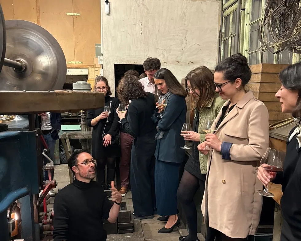 Des invités reçus dans un atelier d’orfèvrerie, un verre à la main